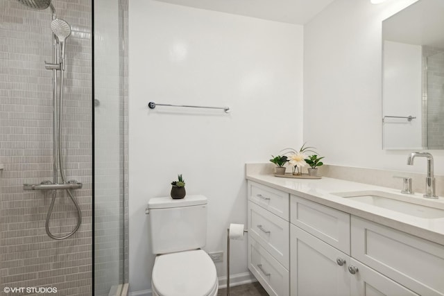 bathroom with a tile shower, vanity, and toilet