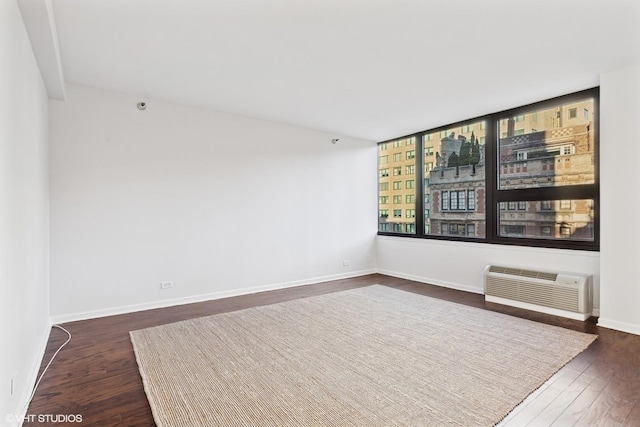 spare room with a wall mounted AC and dark wood-type flooring