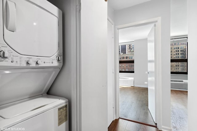 clothes washing area featuring stacked washer / drying machine and dark hardwood / wood-style flooring