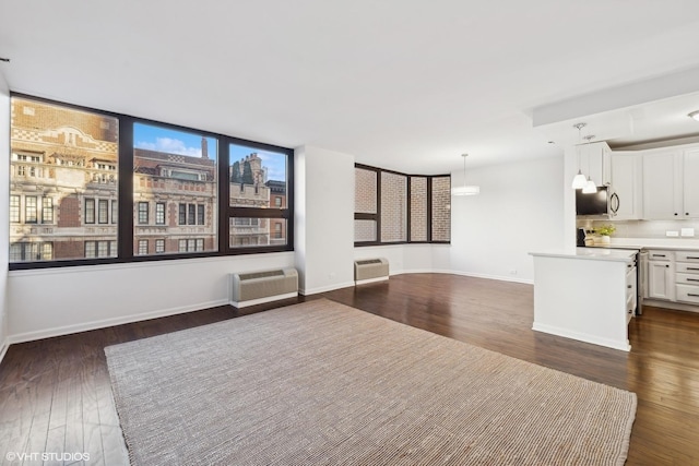 unfurnished living room featuring a wall unit AC and dark wood-type flooring