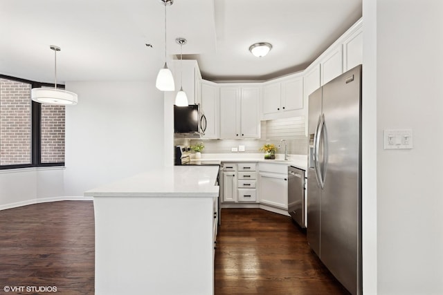 kitchen featuring pendant lighting, dark hardwood / wood-style floors, appliances with stainless steel finishes, tasteful backsplash, and white cabinetry