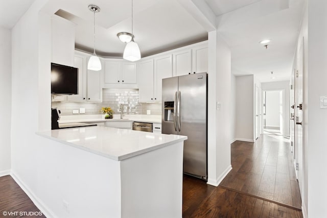 kitchen featuring white cabinetry, sink, hanging light fixtures, stainless steel appliances, and kitchen peninsula