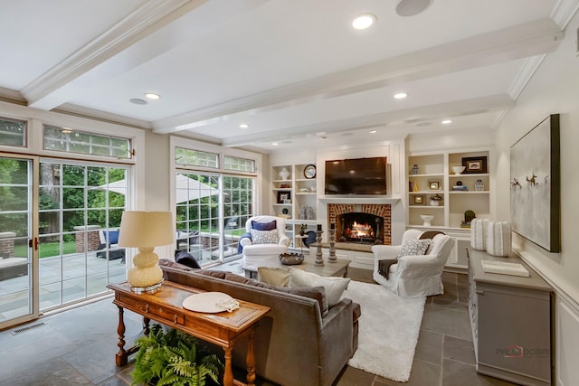 living room featuring crown molding, built in features, beam ceiling, and a brick fireplace