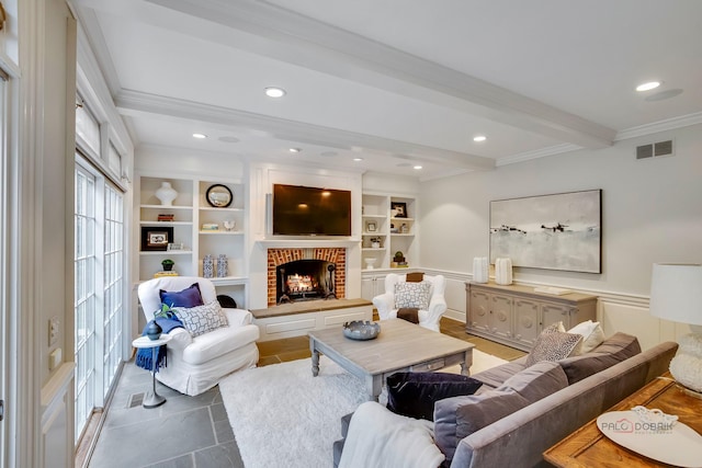 living room featuring built in shelves, a fireplace, beam ceiling, and crown molding