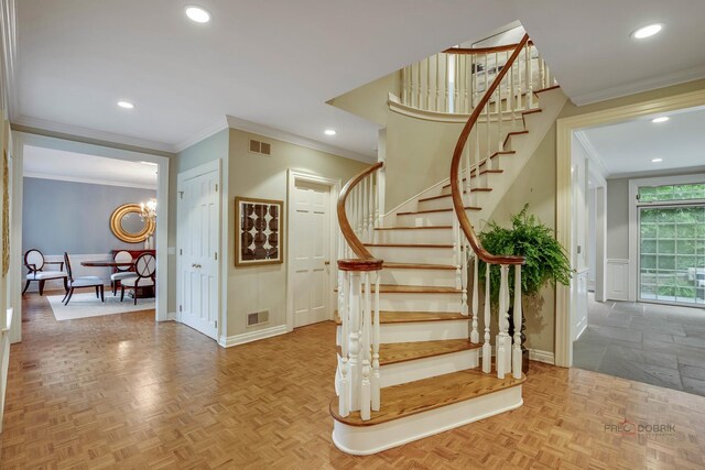 stairway featuring ornamental molding, parquet floors, and a chandelier