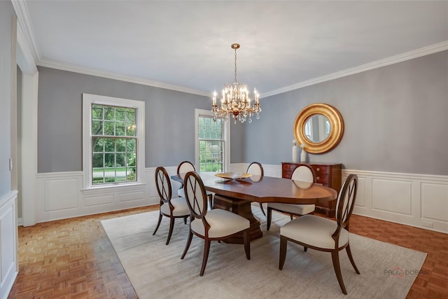 dining room with an inviting chandelier, ornamental molding, and light parquet flooring