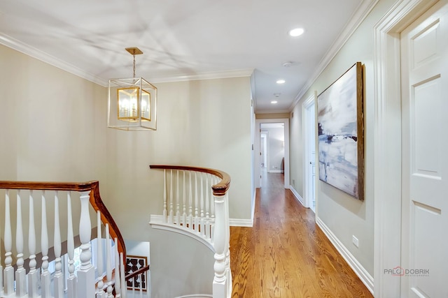 hall featuring an inviting chandelier, crown molding, and light hardwood / wood-style flooring