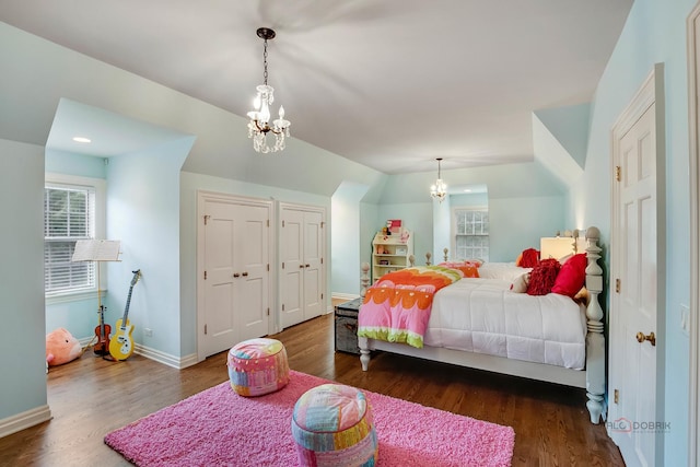 bedroom featuring multiple closets, dark hardwood / wood-style floors, vaulted ceiling, and a notable chandelier