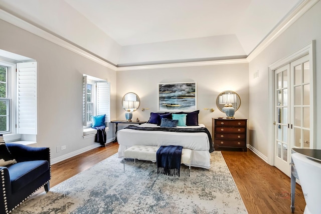 bedroom with a tray ceiling, ornamental molding, french doors, and hardwood / wood-style flooring