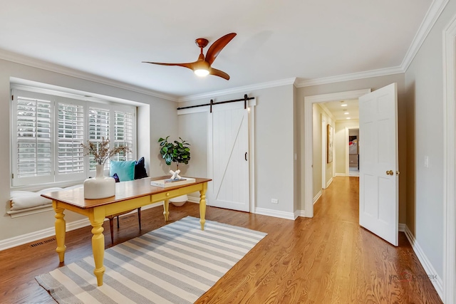 office featuring crown molding, a barn door, ceiling fan, and light hardwood / wood-style flooring