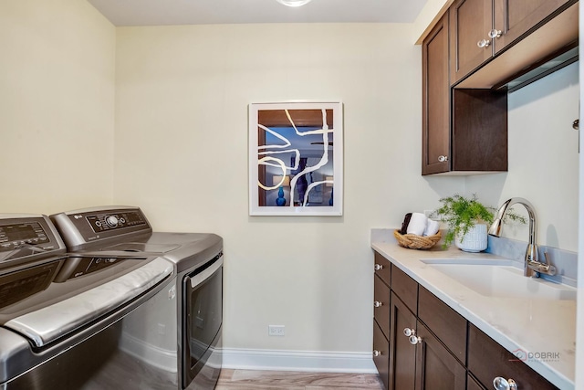 laundry area with light hardwood / wood-style floors, cabinets, separate washer and dryer, and sink