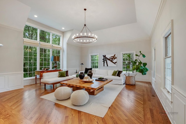 living room featuring an inviting chandelier, a healthy amount of sunlight, and light wood-type flooring