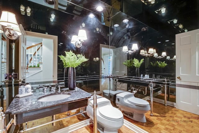 bathroom featuring vanity, parquet flooring, and toilet