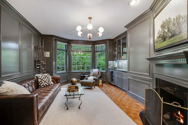 living area featuring sink, a chandelier, beverage cooler, a fireplace, and light parquet floors