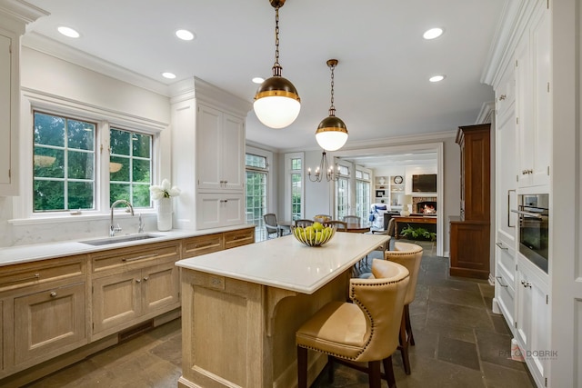 kitchen featuring sink, stainless steel oven, decorative light fixtures, ornamental molding, and a kitchen island