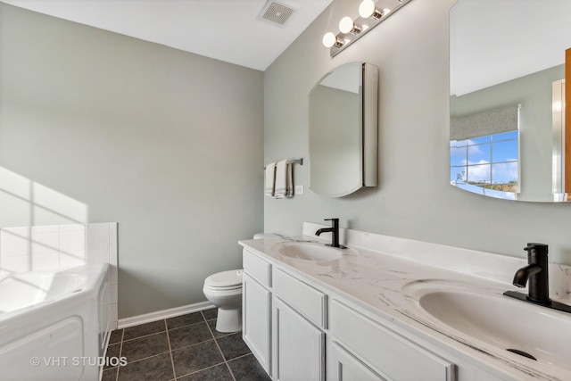 bathroom with tile patterned floors, vanity, toilet, and a tub to relax in