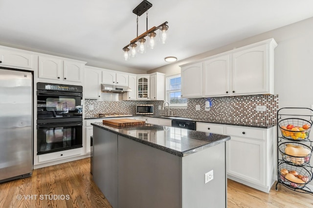 kitchen featuring white cabinets, a center island, light hardwood / wood-style flooring, and black appliances