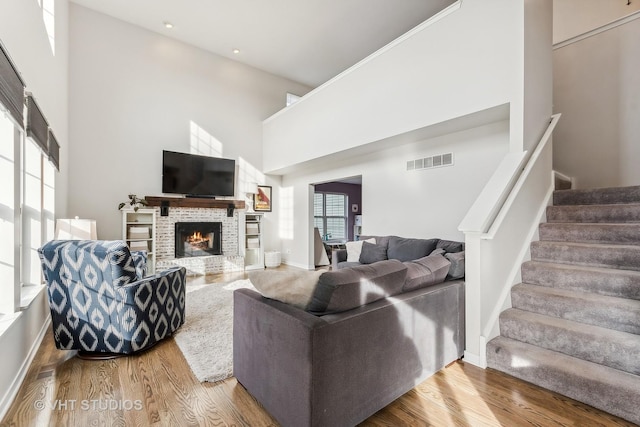 living room with hardwood / wood-style floors, a towering ceiling, and a fireplace