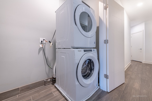 clothes washing area with hardwood / wood-style floors and stacked washer / drying machine