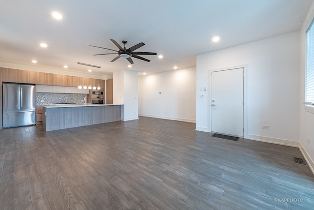 unfurnished living room with dark hardwood / wood-style flooring, ceiling fan, and sink