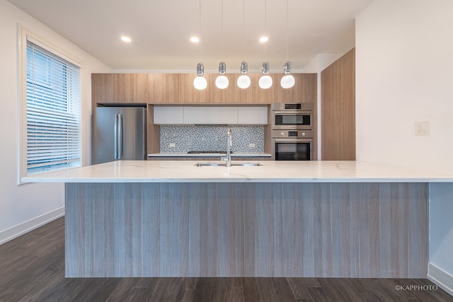 kitchen featuring sink, dark hardwood / wood-style floors, decorative light fixtures, and appliances with stainless steel finishes