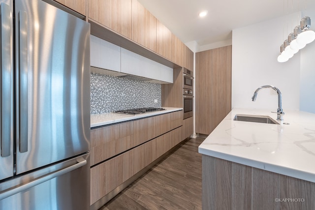 kitchen with light stone countertops, sink, dark hardwood / wood-style flooring, backsplash, and appliances with stainless steel finishes