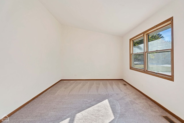 carpeted empty room featuring vaulted ceiling