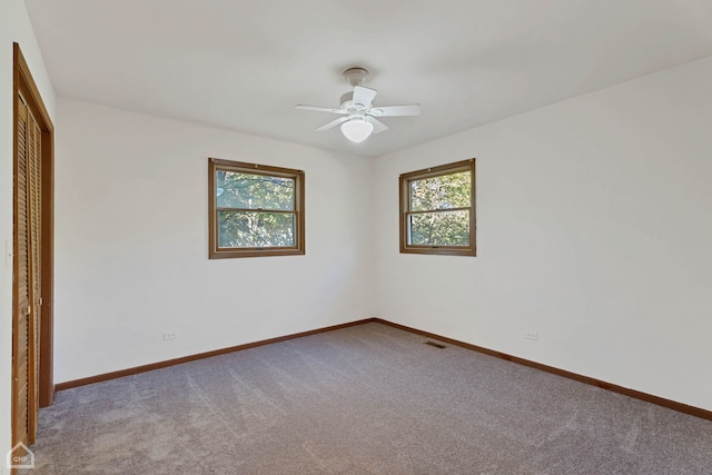 carpeted spare room with ceiling fan and plenty of natural light