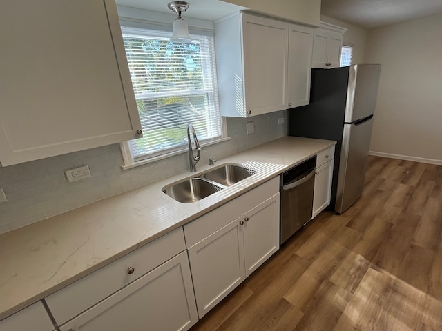 kitchen featuring hanging light fixtures, white cabinetry, light wood-type flooring, sink, and stainless steel appliances