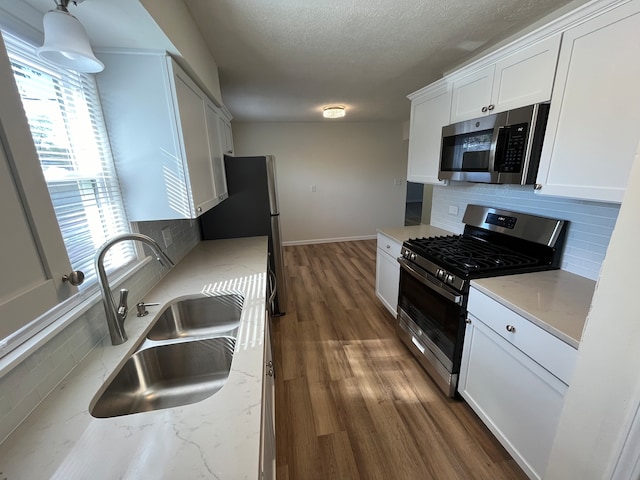 kitchen with white cabinetry, decorative backsplash, stainless steel appliances, and sink