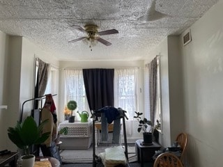 exercise room with ceiling fan, a textured ceiling, and a healthy amount of sunlight