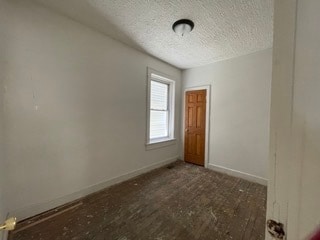 unfurnished room featuring dark wood-type flooring and a textured ceiling