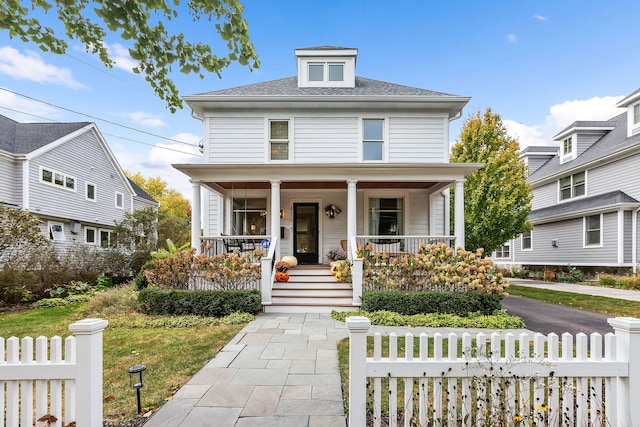 american foursquare style home featuring a porch and a fenced front yard