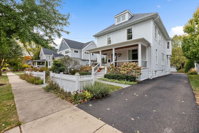 american foursquare style home featuring a residential view, fence, and a porch