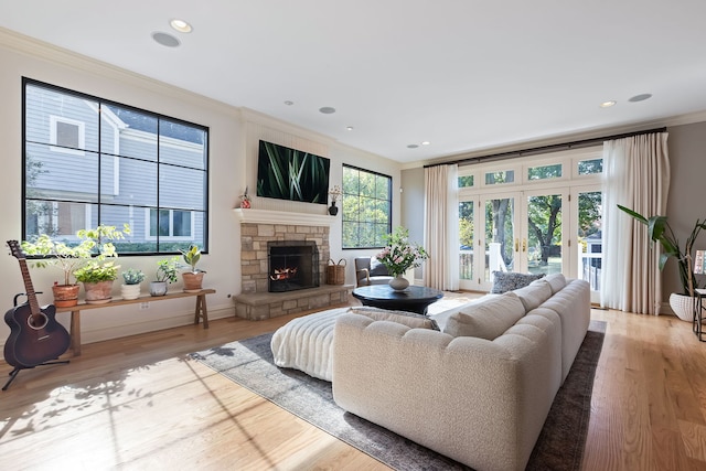 living area featuring recessed lighting, a fireplace, light wood-style floors, french doors, and crown molding