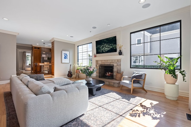 living area with a fireplace, recessed lighting, light wood-style flooring, ornamental molding, and baseboards