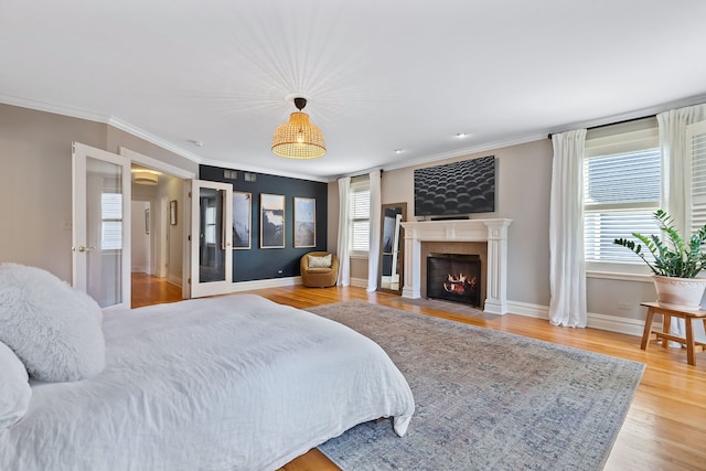 bedroom with a fireplace with flush hearth, multiple windows, crown molding, and wood finished floors