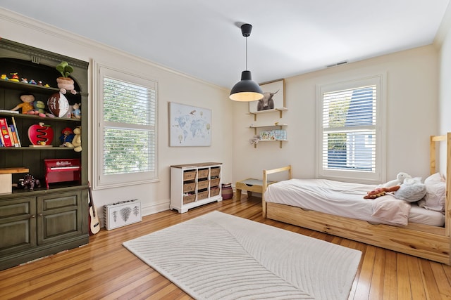 bedroom with visible vents, wood finished floors, and ornamental molding