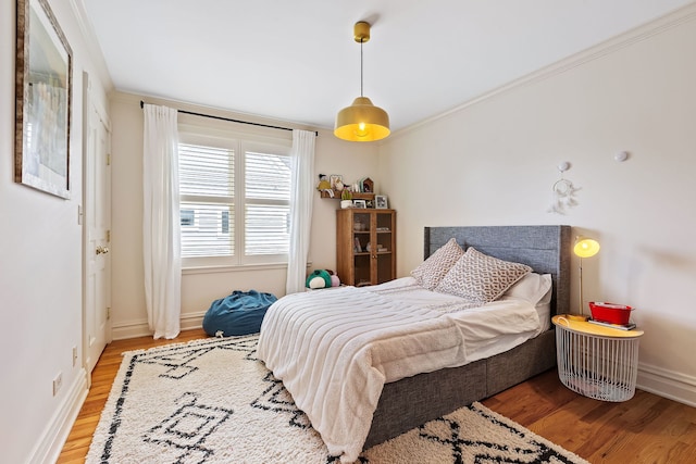 bedroom with crown molding, baseboards, and wood finished floors