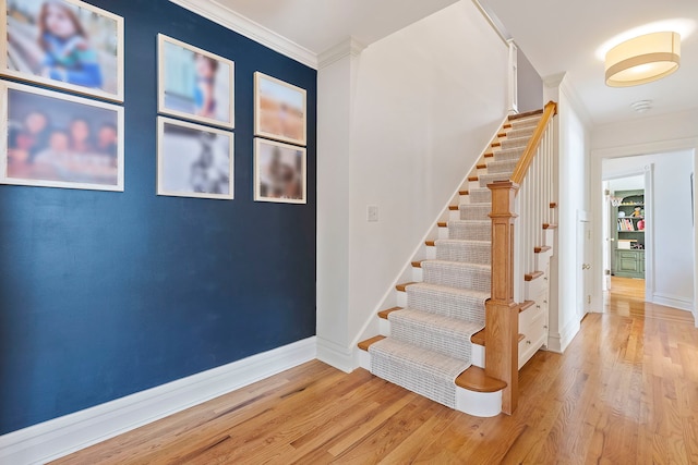 staircase featuring baseboards, ornamental molding, and wood finished floors