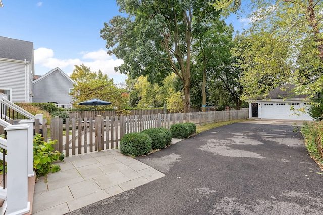 view of patio with a garage, an outbuilding, and fence