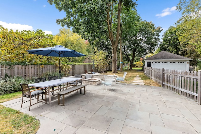 view of patio featuring fence, a fire pit, outdoor dining area, and an outbuilding