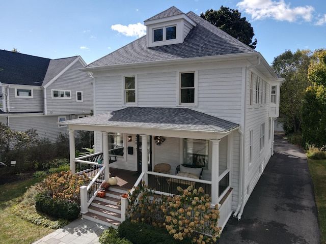 traditional style home featuring a shingled roof and a porch