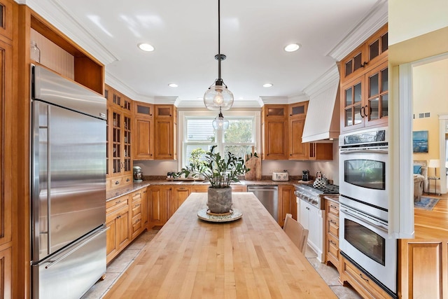 kitchen with appliances with stainless steel finishes, light countertops, decorative light fixtures, and glass insert cabinets