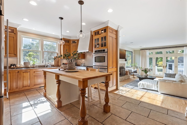 kitchen featuring recessed lighting, butcher block counters, glass insert cabinets, open floor plan, and a stone fireplace