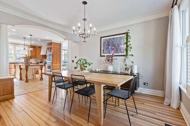 dining room featuring ornamental molding, light wood-style flooring, decorative columns, and baseboards