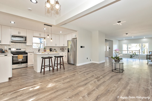 kitchen featuring a breakfast bar, white cabinets, stainless steel appliances, and light wood-type flooring