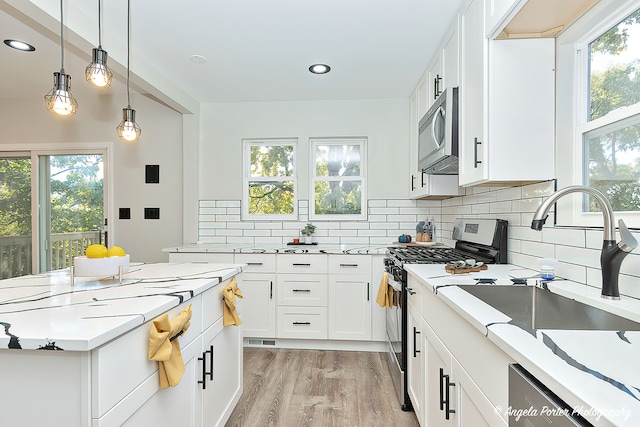 kitchen featuring light hardwood / wood-style flooring, white cabinets, stainless steel appliances, and a wealth of natural light