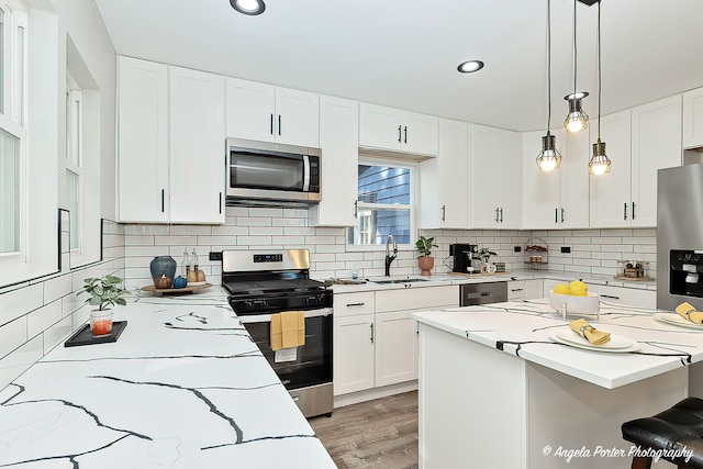 kitchen with appliances with stainless steel finishes, sink, backsplash, hanging light fixtures, and white cabinets