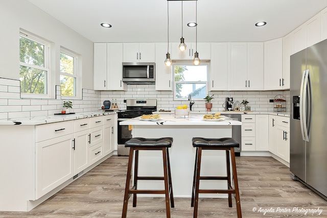 kitchen featuring a kitchen island, appliances with stainless steel finishes, white cabinetry, and light hardwood / wood-style floors